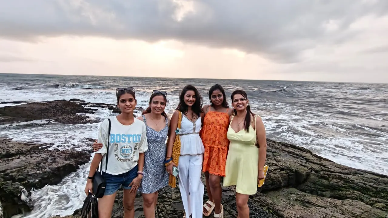 Five travellers on the rocks at a quiet Goa beach at sunset