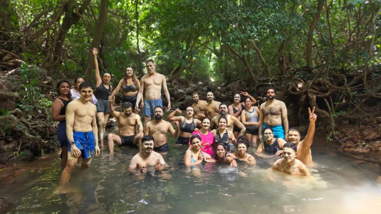 A large group in the jungle mud bath stream, arms raised